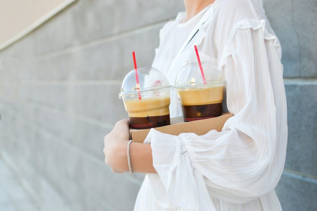 A person holding a drink served in a plastic cup